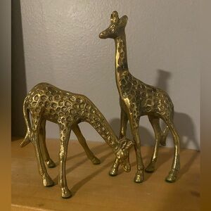 A pair of vintage solid brass giraffe figurines with textured patterns.